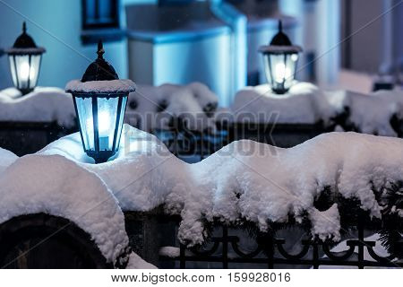 city night scene with street christmas lanterns during snowfall