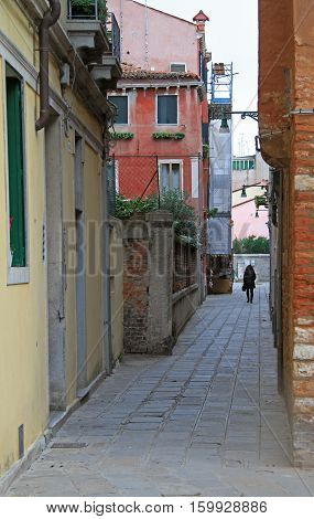 Venice Italy - November 23 2015: woman is walking by the narrow street in Venice Italy