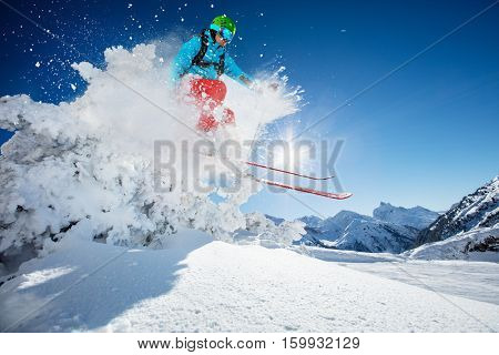 Freeride skier jumping from rock in freeze motion of snow powder.