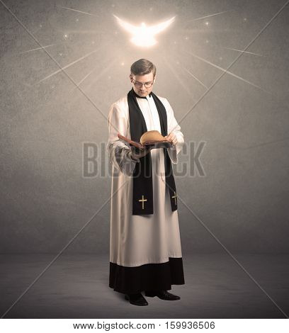 A holy priest reading a prayer from the holy bible with illustrated glowing angel above his head concept.