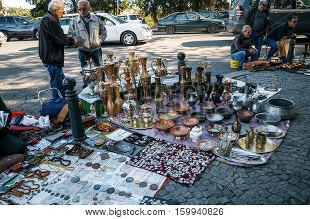 Tbilisi Georgia - October 15 2016: Traders and sellers of flea market on Dry bridge having a lot of vintage pitchers plates handmade banknotes souvenirs and retro staff for the customers.