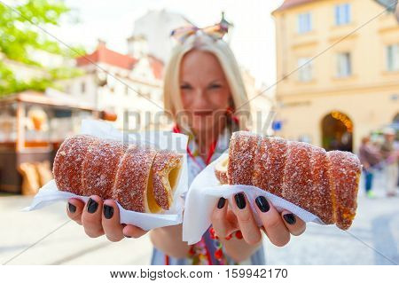 Young female tourist with traditional czech dessert called trdelnik in Prague. Czech Republic. Outdoor