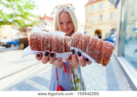 Young female tourist with traditional czech dessert called trdelnik in Prague. Czech Republic. Outdoor