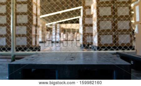 soft focus of empty black pallet in warehouse with stack of cartons background