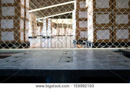 empty black pallet in warehouse with stack of a several cartons background