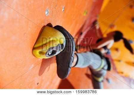 Showing strength. Young delighted pretty woman training hard in climbing gym while using equipment and climbing up the wall.