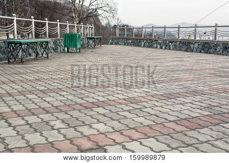 Paved viewing platform with wooden bench. Autumn day.