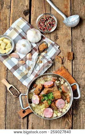 View From Above Of Old Saucepan With Garlic Soup, Fresh Garlic Bulbs, Cloves, Colored Pepper, Wooden