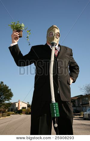 素敵なスーツと、ガスマスクで環境に優しいビジネス男 t を保存する緑の植物を保持します。