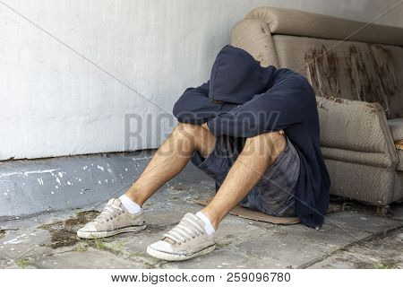 Depressed, Desperate Young Man Sitting On The Building Rooftop Terrace, Wearing Hoodie, Holding Head