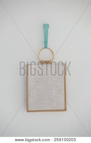Close-up of bag hanging on hook against white wall