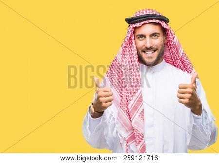 Young handsome man wearing keffiyeh over isolated background success sign doing positive gesture with hand, thumbs up smiling and happy. Looking at the camera with cheerful expression, winner gesture.