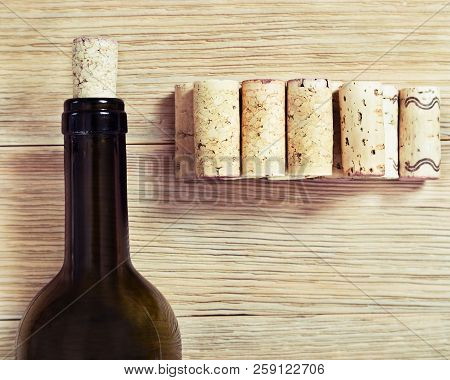 Glass Bottle Of Red Wine With Corks. On Old Wooden Table. Top View. Soft Focus. Toned Photo.