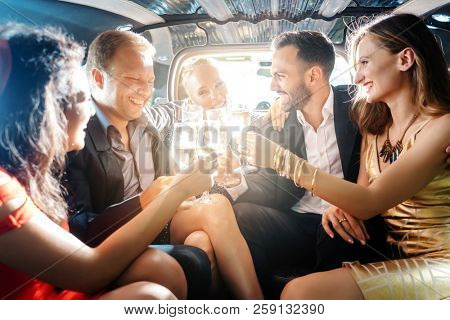 Crowd of party people in a limo with drinks, woman and men having fun 