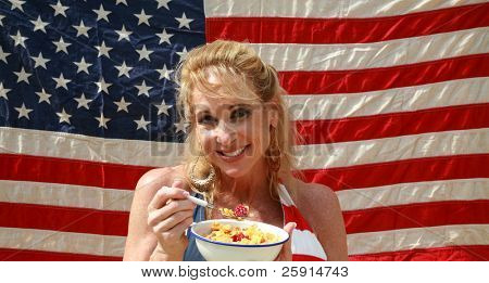 una donna si gode una ciotola di cereali con latte e lamponi una mattina davanti alla sua bandiera americana