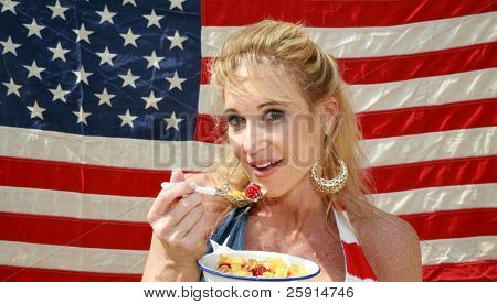 una donna si gode una ciotola di cereali con latte e lamponi una mattina davanti alla sua bandiera americana