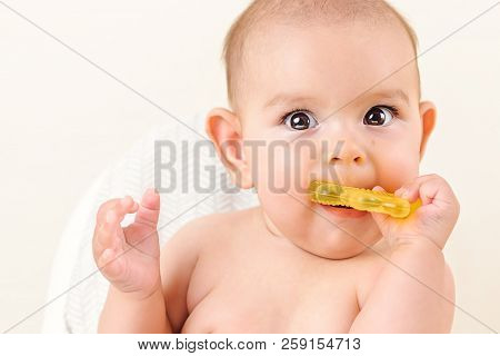 Cute Baby Infant Kid Biting Sitting In Highchair And Chewing Yellow Eething Toy Copy Space Bright Mi