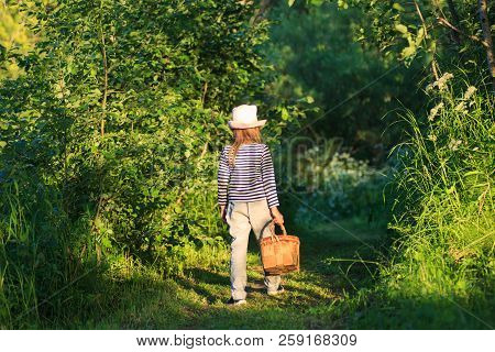 Young Girl Walking On A Path Through Green Woods Carrying A Birchbark Basket