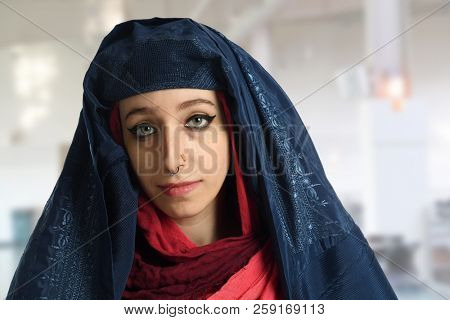 Young Islamic woman wearing burqa with veil open inside building