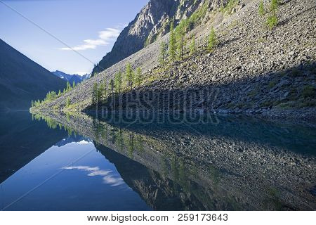 Reflection Of The Shore Of The Lake In The Watery Surface. Early Sunny Morning. The Large (lower) Sh