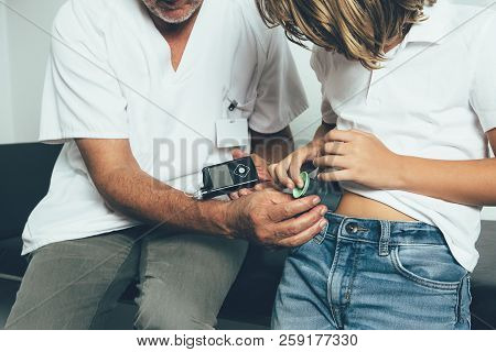 Cropped View Of A Diabetic Child Inserts The Insertion System Of The Infusion Set Of An Insulin Pump