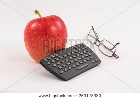 Red Apple With A Mini Keyboard And Glasses On A White Background. Fun Business Still Life.