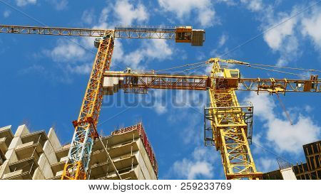 Two Cranes And Blue Sky. Building Under Construction. Construction Site.