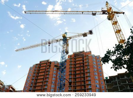 Two Tower Cranes Against The Background Of Buildings Under Construction. Construction Site.