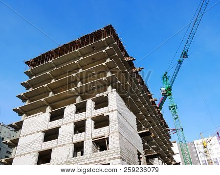 Concrete Building And Crane Against Blue Sky. Construction Site Background