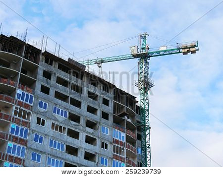 Crane And Concrete Building Against Bkue Sky. Construction Site.