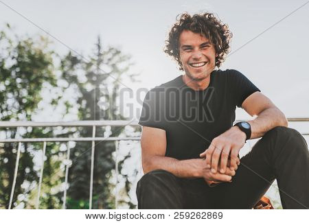 Low View Shot Of Happy Stylish Young Man Wears Black T-shirt And Wirstwatch On The Street. Happy Smi