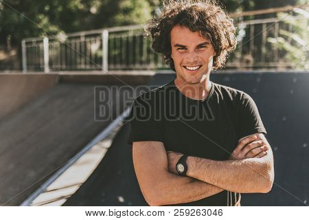 Portrait Of Stylish Young Man Wears Black T-shirt And Wirstwatch On The Street. Happy Smiling Man Po