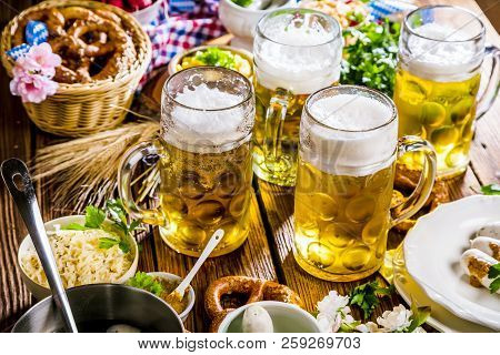 Oktoberfest Beer, Pretzels And Various Bavarian Specialties On Wooden Background