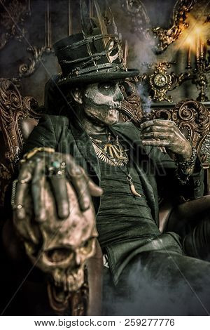 Halloween. A man with a skull makeup dressed in a tail-coat and a top-hat is in the old castle. Baron Saturday. Baron Samedi. Dia de los muertos. Day of The Dead. Old vintage interior.