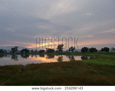 Landscape With A Lagoon With Trees On The Shore, During The Sunset
