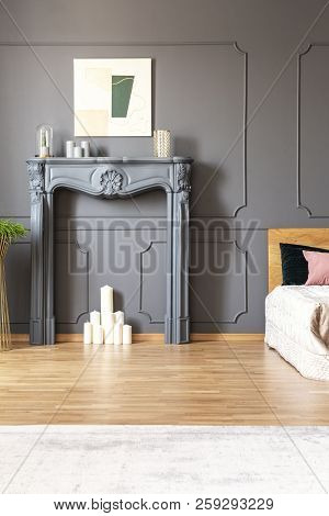 White Candles In A Fireplace Portal Set In A Grey Bedroom Interior With Wall Molding, Carpet And Bed