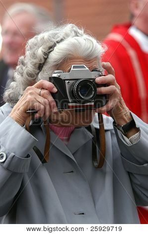 Paparazzi antiga: uma mulher de idade tirando fotos com uma câmera retro.
