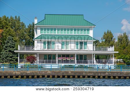 white cottage with front porch and green roof on lake seawall