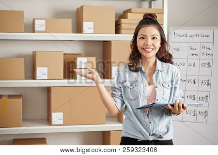 Portrait Of Asian Smiling Postwoman Preparing Parcels For Delivery To Customers