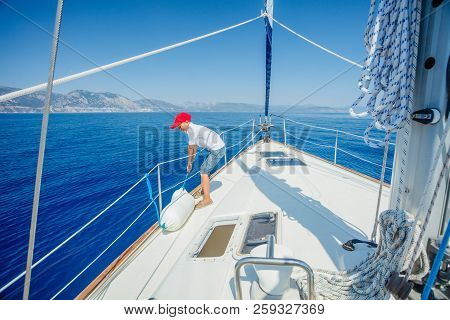 Little Boy On Board Of Sailing Yacht On Summer Cruise.