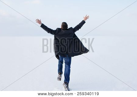 Man Standing On The Shore Of A Frozen Sea. Downshifting. Lonely Man In Casual Clothes On The Sea Coa