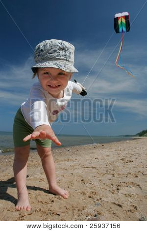 Lille pige flyvende kite på stranden