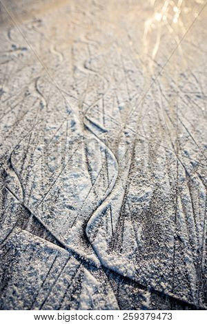 Surface of outdoor ice with snow at sunset, replete with skate marks. Abstract Ice background