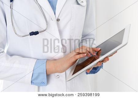 Woman Doctor Using Tablet Computer While Standing Straight In Hospital Closeup. Healthcare, Insuranc