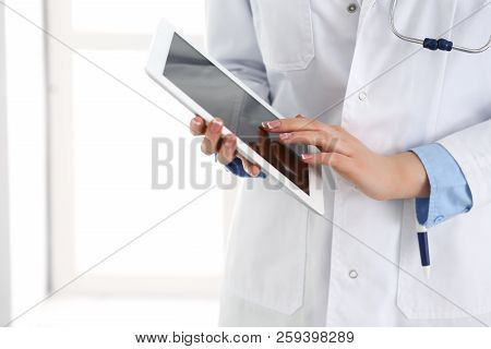 Woman Doctor Using Tablet Computer While Standing Straight In Hospital Closeup. Healthcare, Insuranc