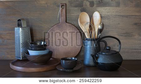 Crockery, Clayware, Dark Utensils And Other Different Stuff On Wooden Tabletop. Kitchen Still Life A