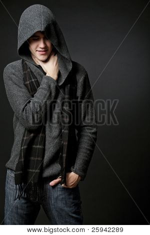 Jeune homme séduisant heureux portant un chandail gris à capuche.