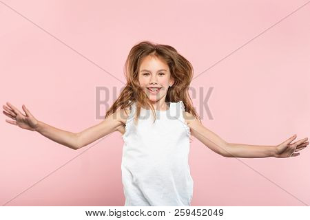 Freedom And Child Carefree Lifestyle. Smiling Young Girl Jumping Spreading Hands In The Air. Excited