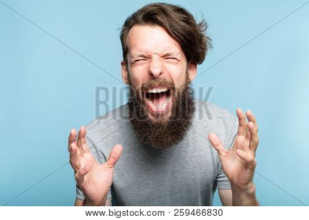 Emotional Breakdown. Angry Enraged Infuriated Crazy Man Screaming. Portrait Of A Young Bearded Guy O