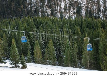 Alpine Transportation Vehicles On Cableway, Traveling Over Snowy Fir Trees, Through The Alps Mountai
